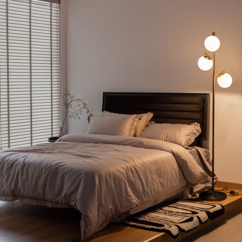 Kolmiliekkinen kultainen lattiavalaisin lasivarjostimilla ja jalkakytkimellä